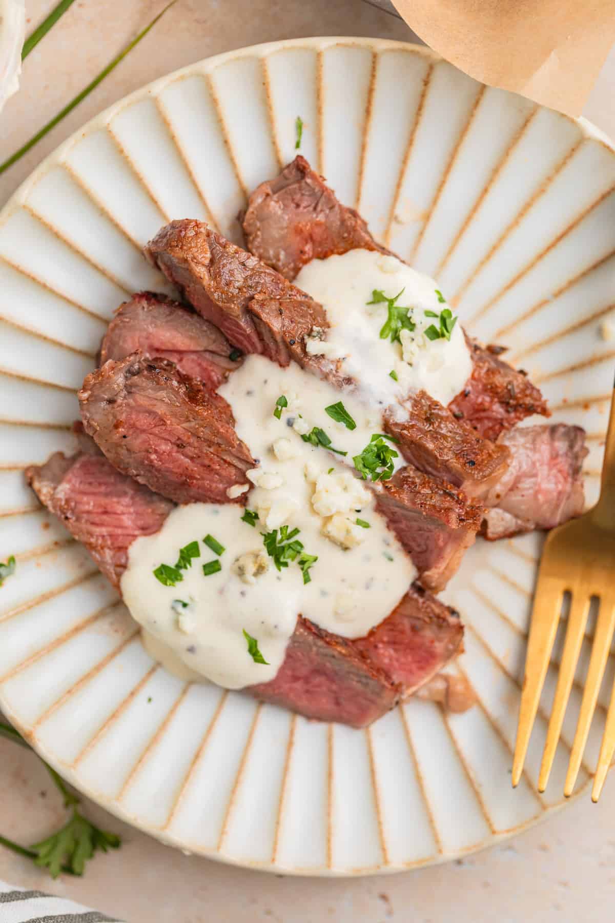 Sliced grilled ribeye steak sliced and served on plate with gorgonzola sauce.