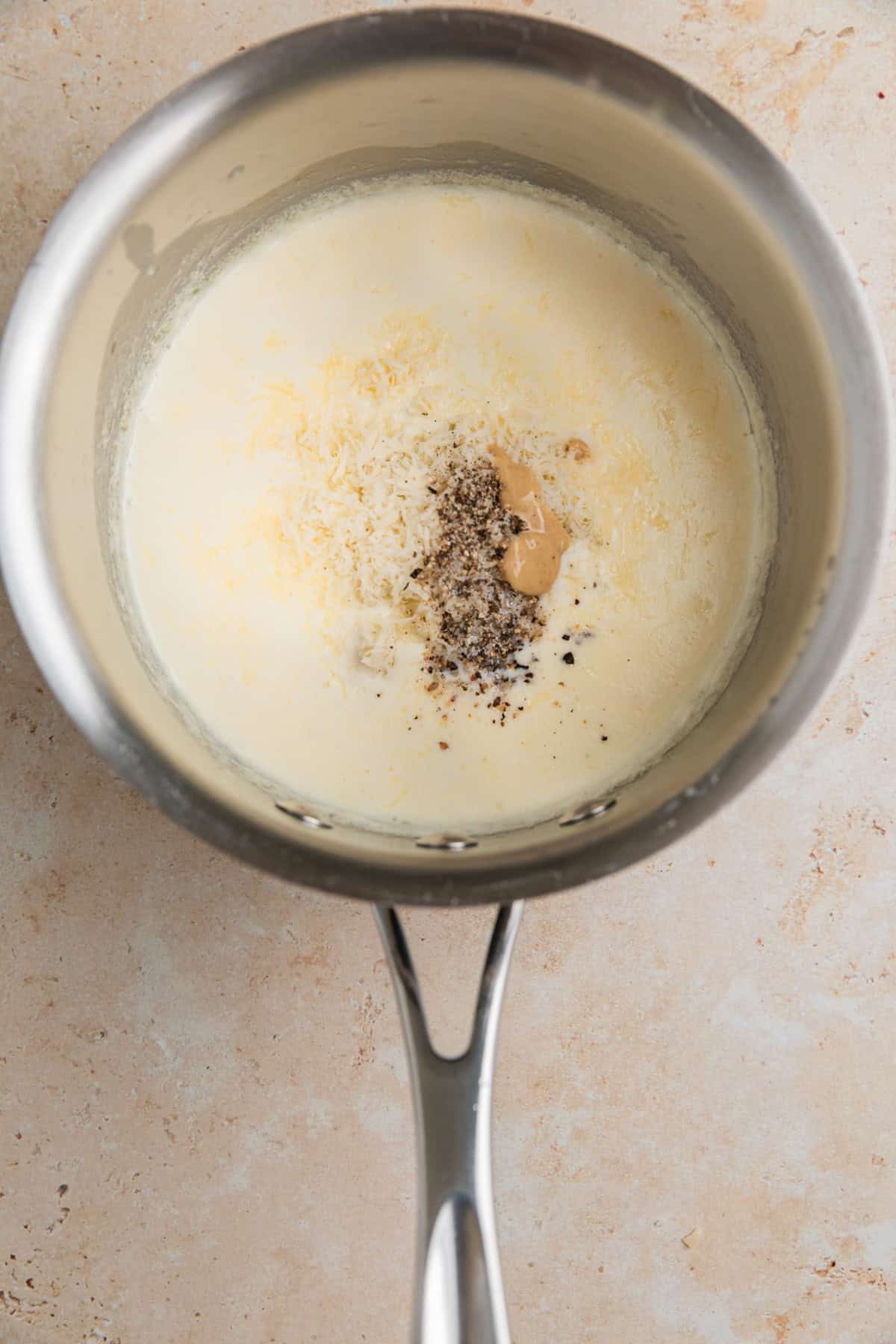 Parmesan, gorgonzola and other ingredients added to sauce pan with cream.