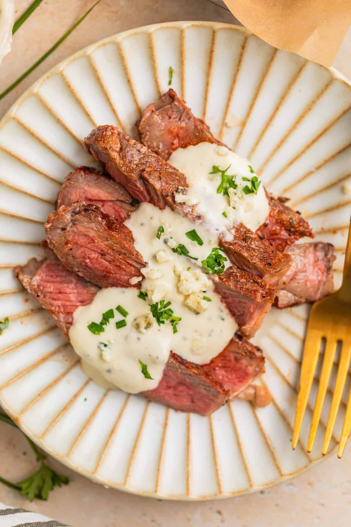 Sliced grilled ribeye steak sliced and served on plate with cheese sauce.