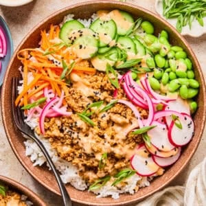 Rice bowl with ground turkey, bang bang sauce, cucumber, carrots and other ingredients.