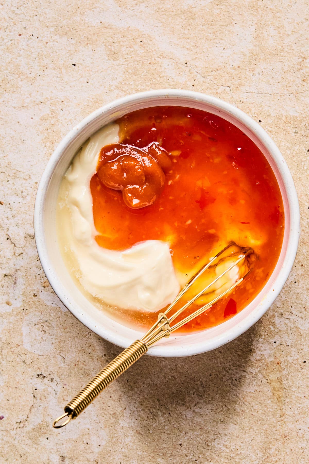 Mayonnaise, sriracha, honey, and ingredients for bang bang sauce in glass dish.