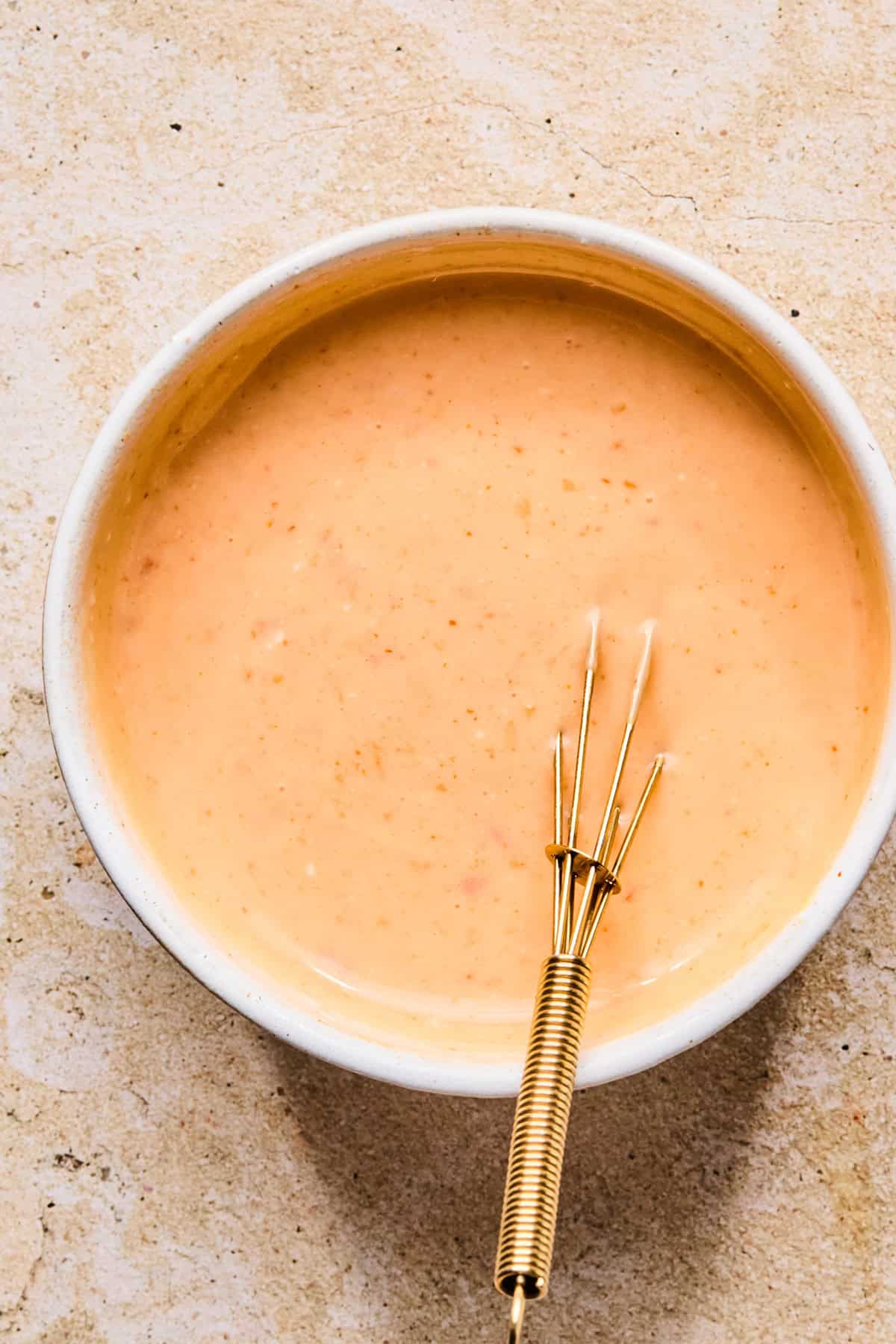 Bang bang sauce in glass bowl with whisk.