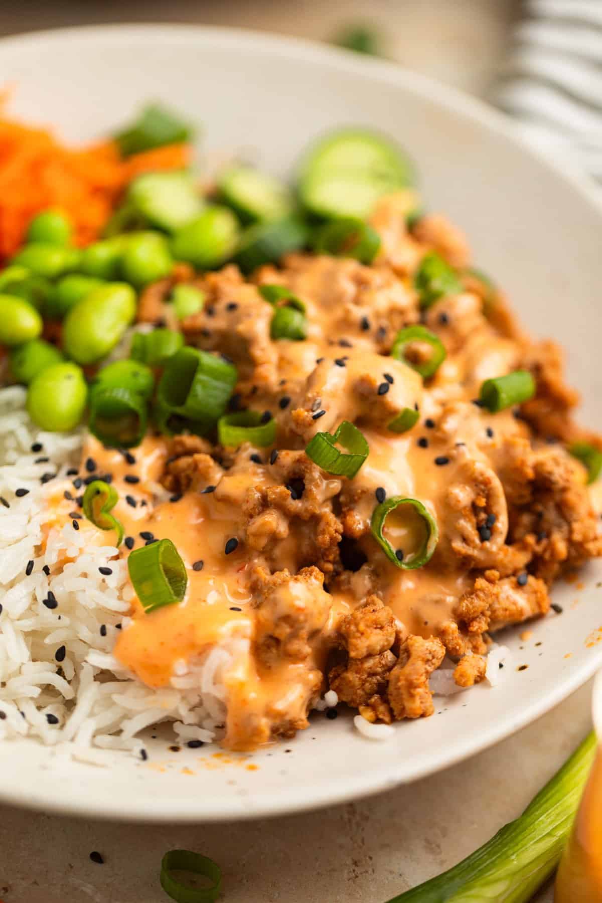 Ground turkey rice bowl topped with bang bang sauce and sesame seeds.