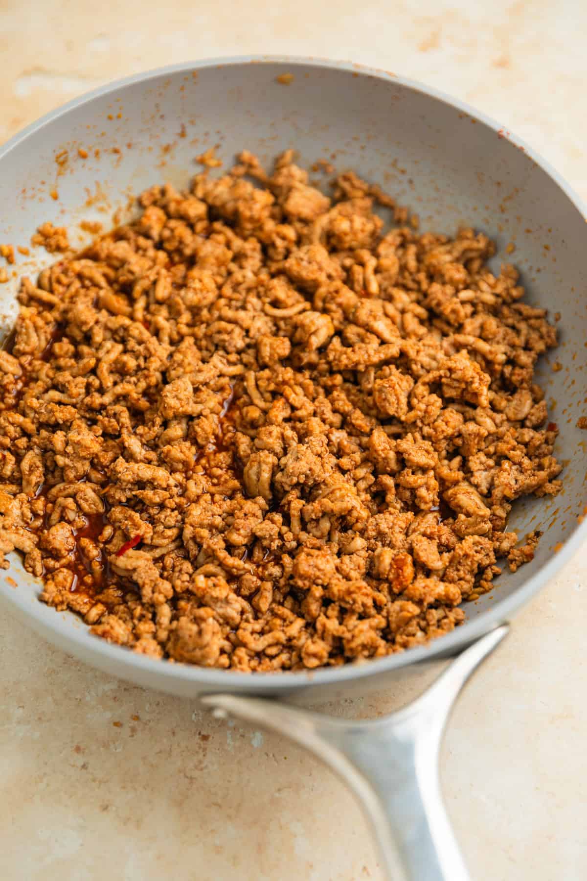 Skillet with ground turkey browned in sauce.