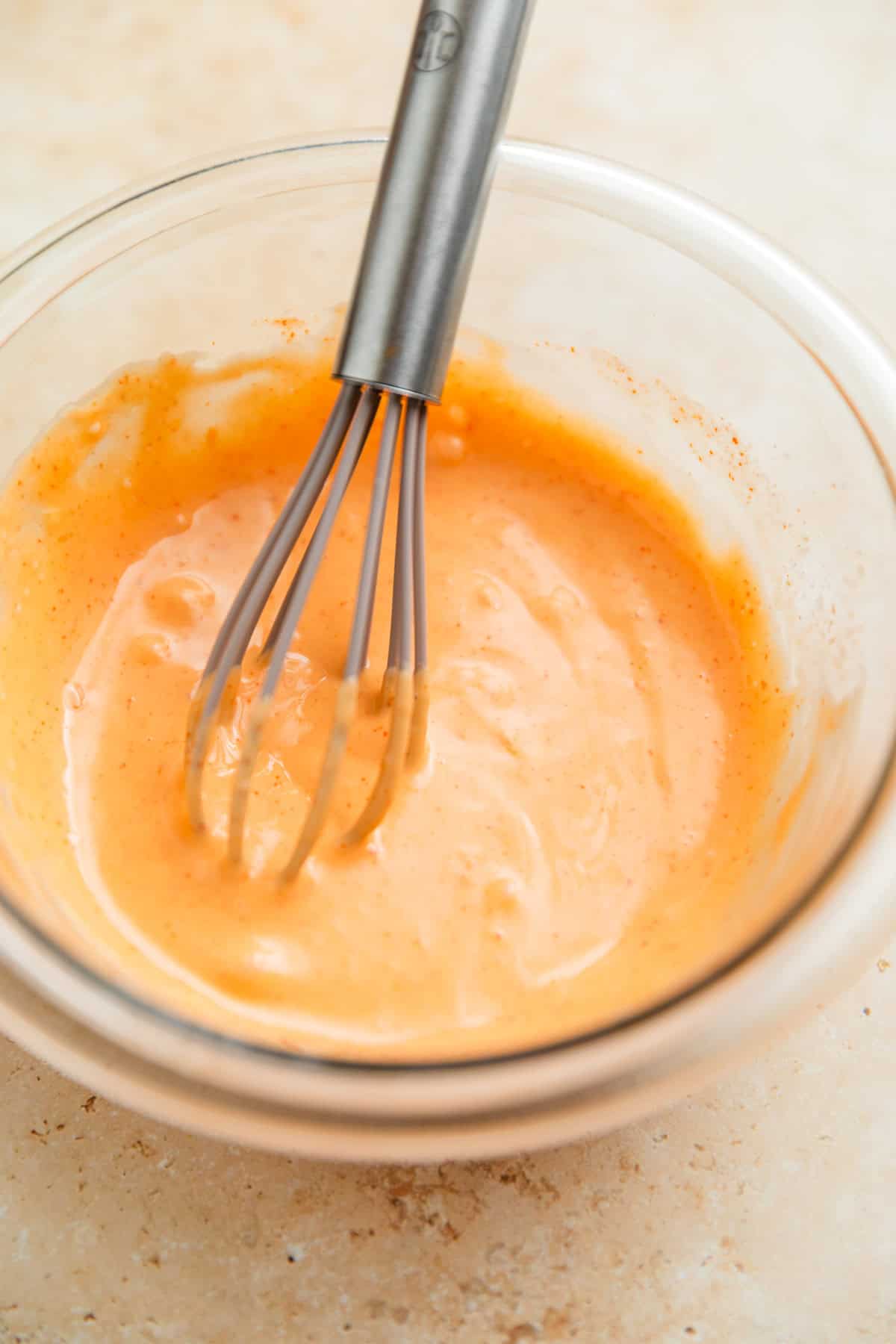 Bang bang sauce in glass bowl with whisk.
