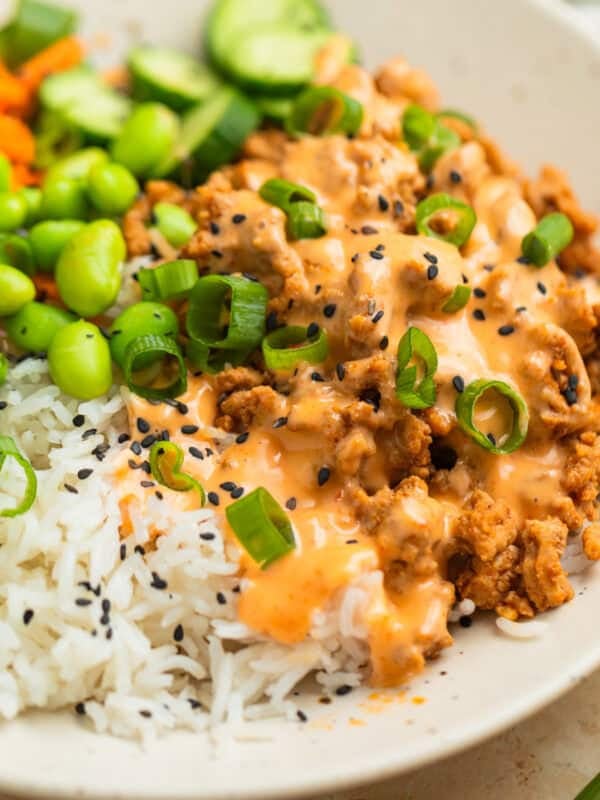 Ground turkey rice bowl with bang bang sauce over top with edamame, cucumber, and more.