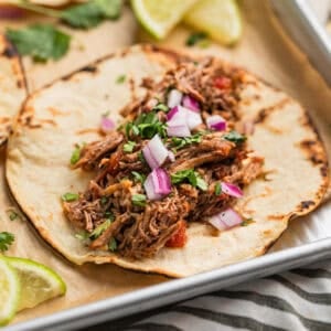 Shredded beef taco topped with cilantro and red onion.