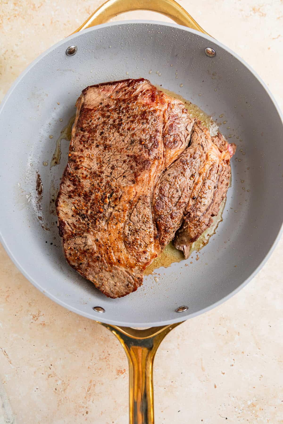 Seared chuck roast in pan.