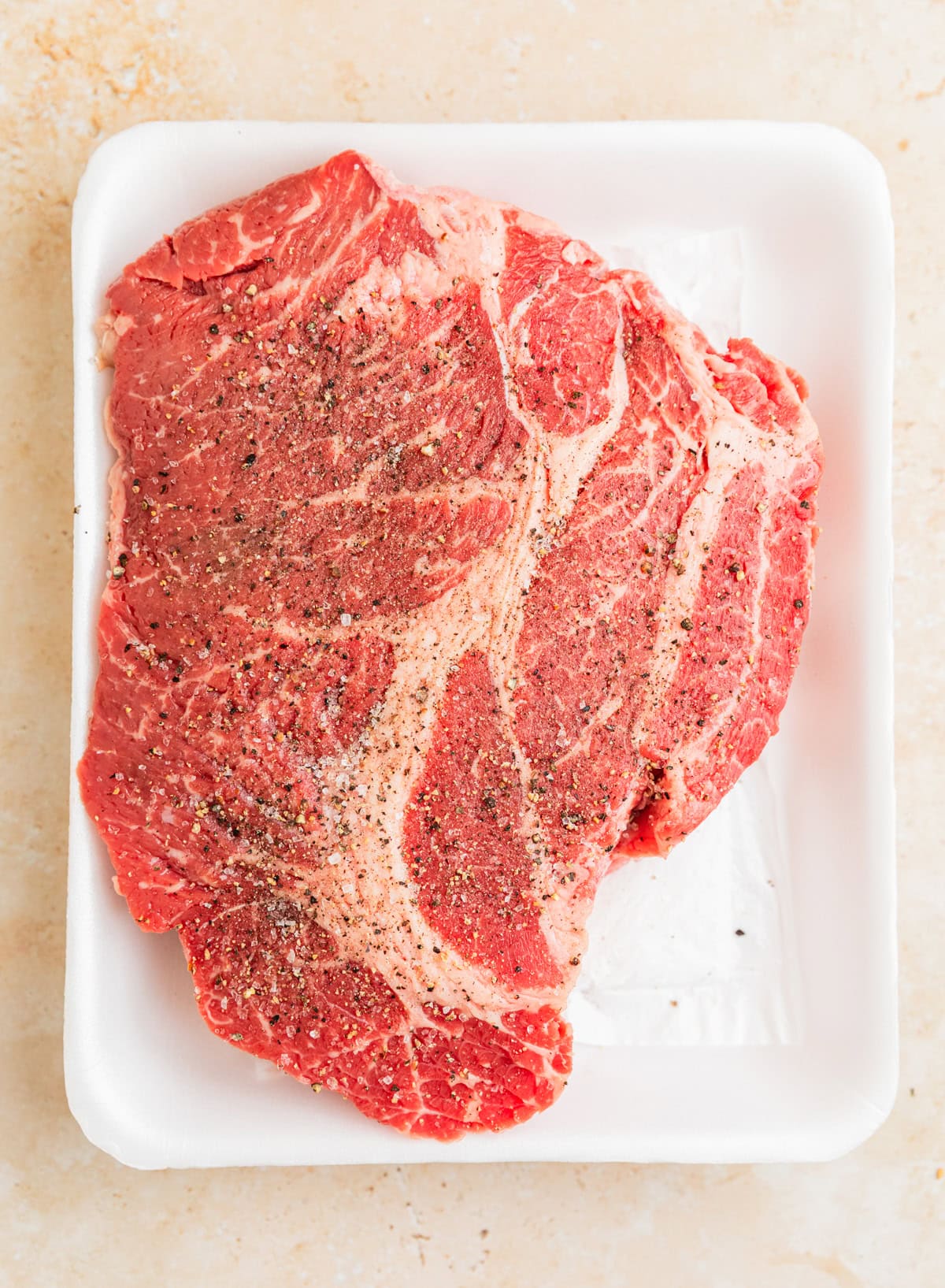Piece of raw chuck roast seasoned before searing.