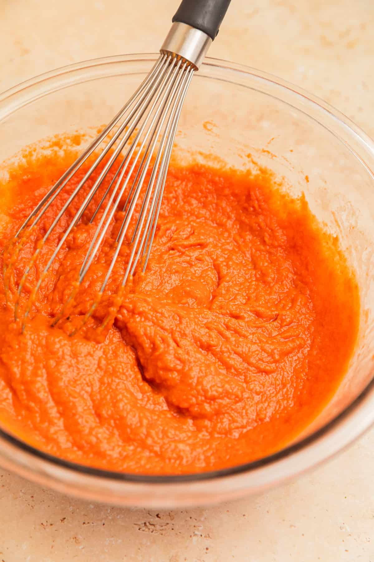 Pumpkin mixture in glass bowl with whisk.