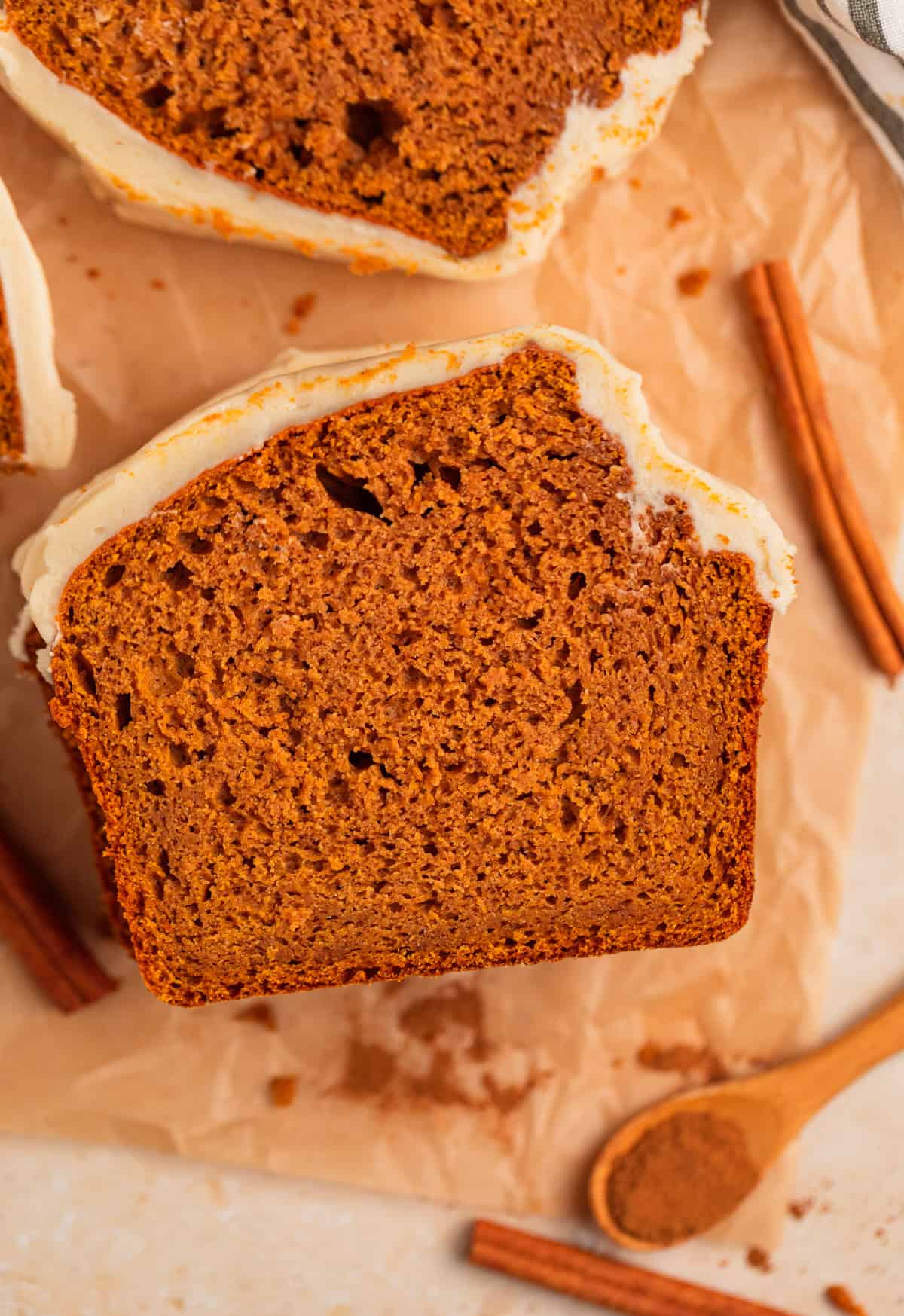 Slice of cake mix pumpkin bread with cream cheese frosting on parchment.