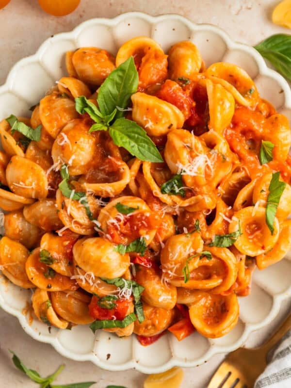Plate with cherry tomato pasta topped with fresh chopped basil and parmesan.