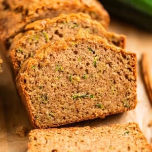 Slices of zucchini bread propped on each other on parchment paper.