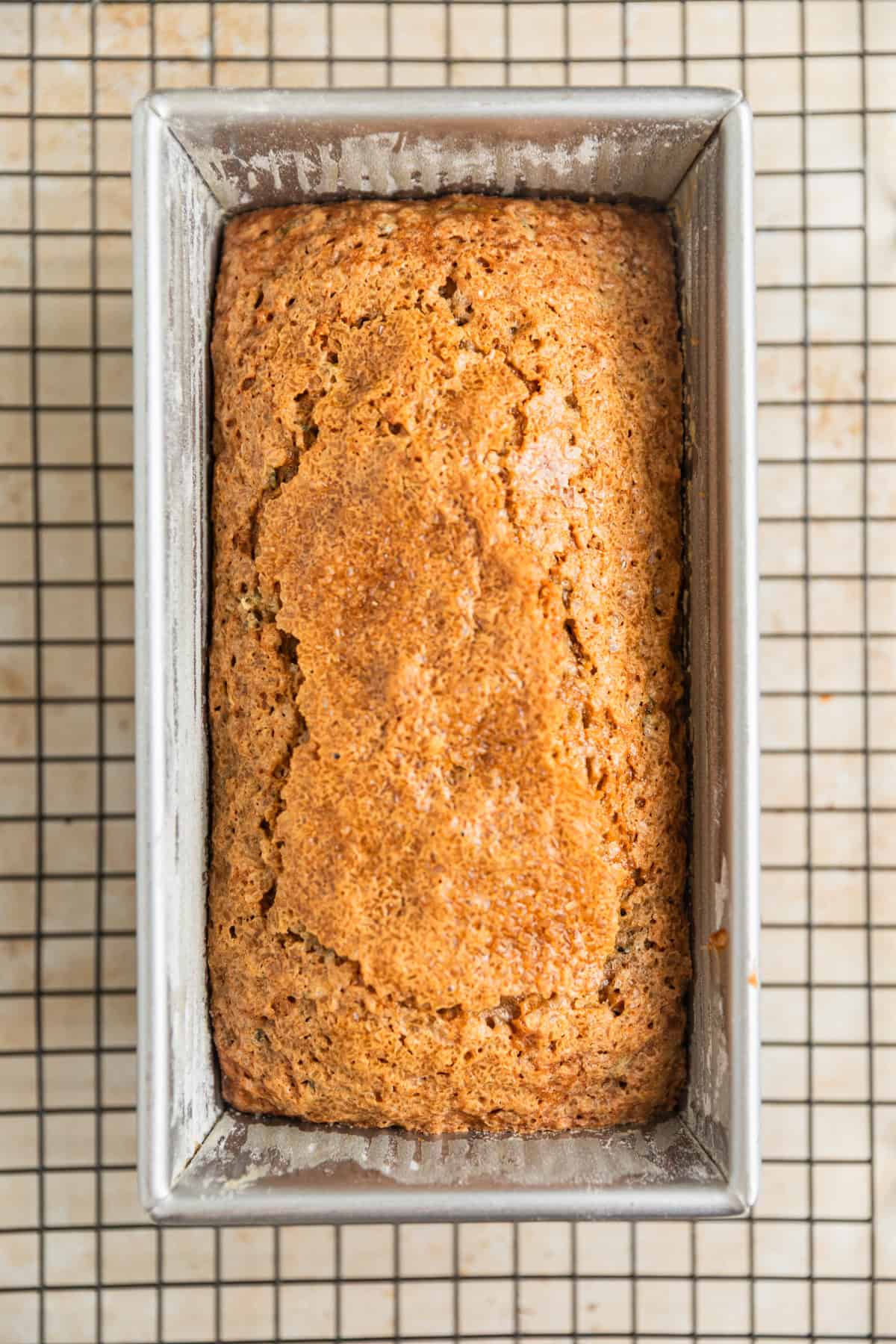 Baked zucchini bread in pan on cooling rack.