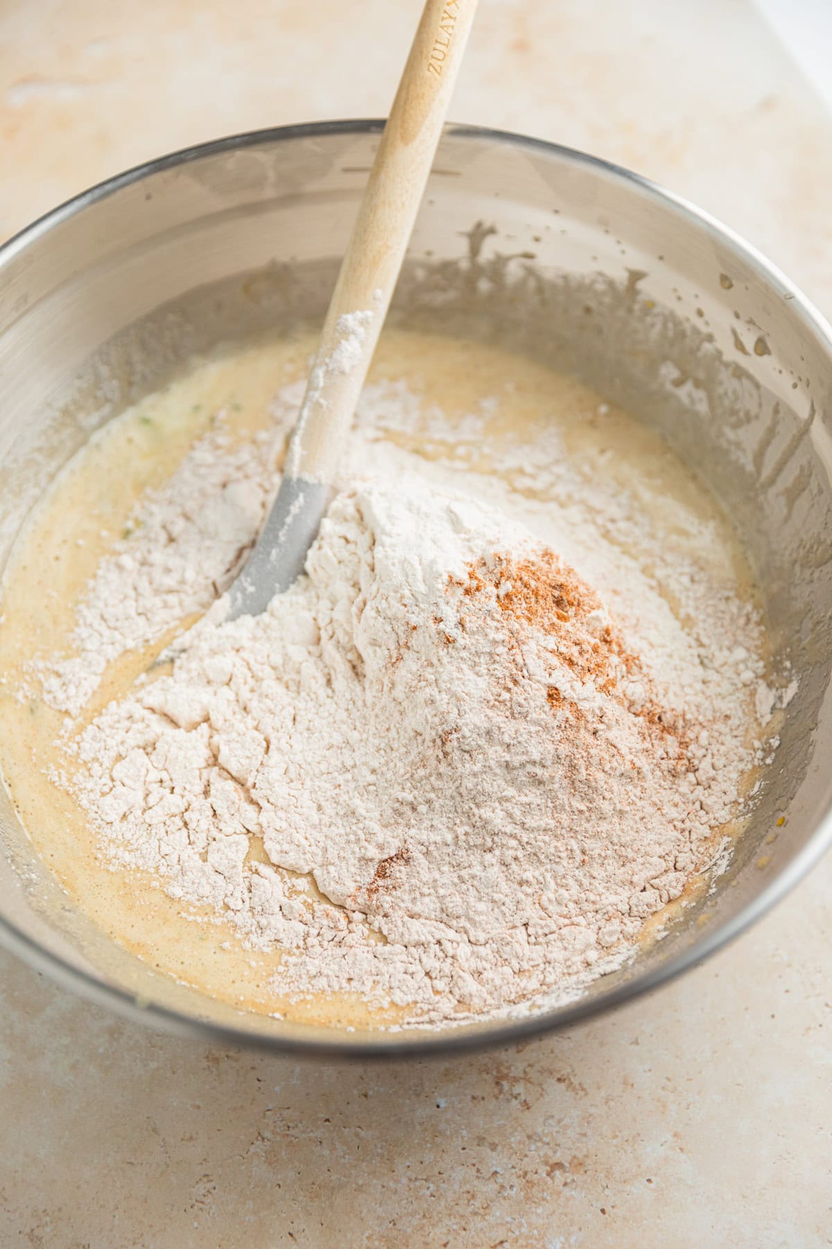Dry ingredients added to wet ingredients in glass mixing bowl.