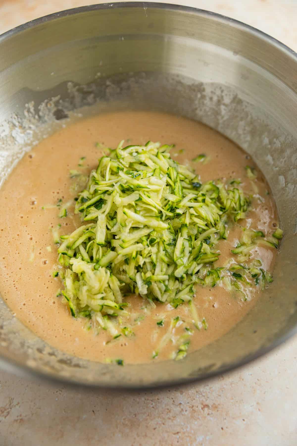 Shredded zucchini added to zucchini bread batter mixture.