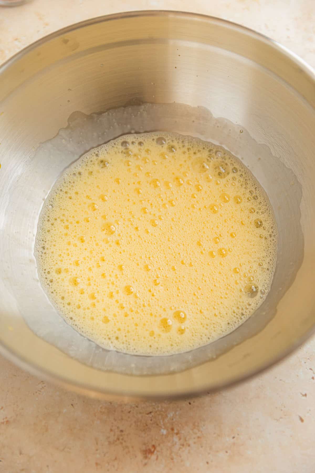 Beaten eggs in stainless steel bowl.