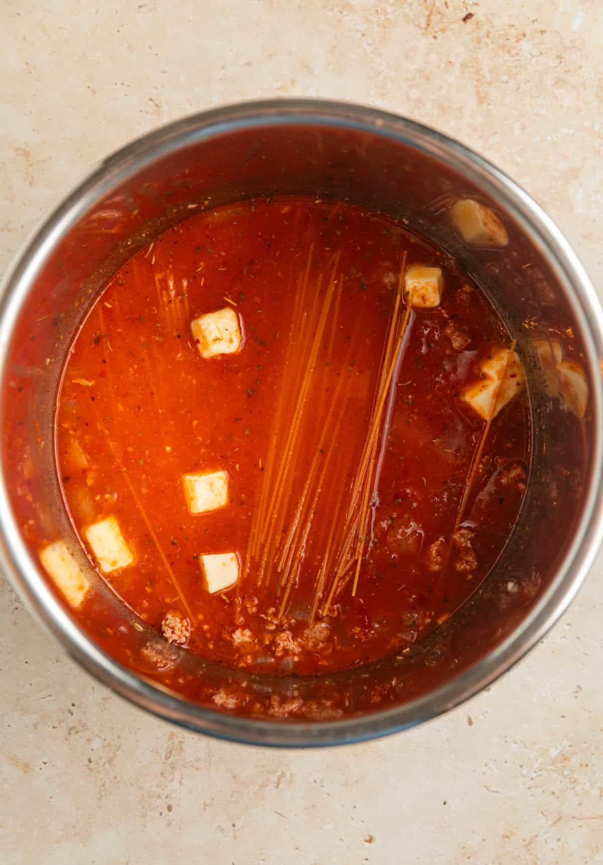 Pasta, cubed butter, marinara sauce and broth added to Instant pot with browned meat.