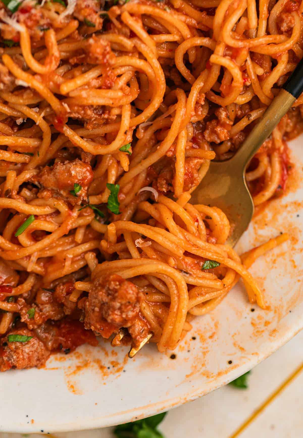 Forkful of pasta and meat sauce on plate.