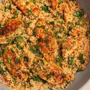 Herbed chicken and rice in pan topped with chopped parsley.