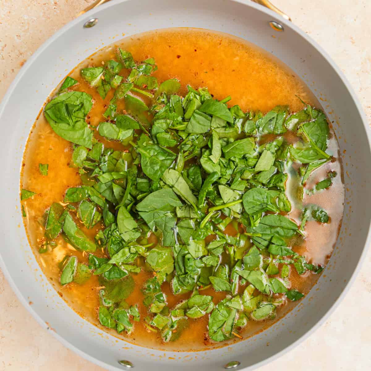 Broth, rice and chopped spinach added to skillet.