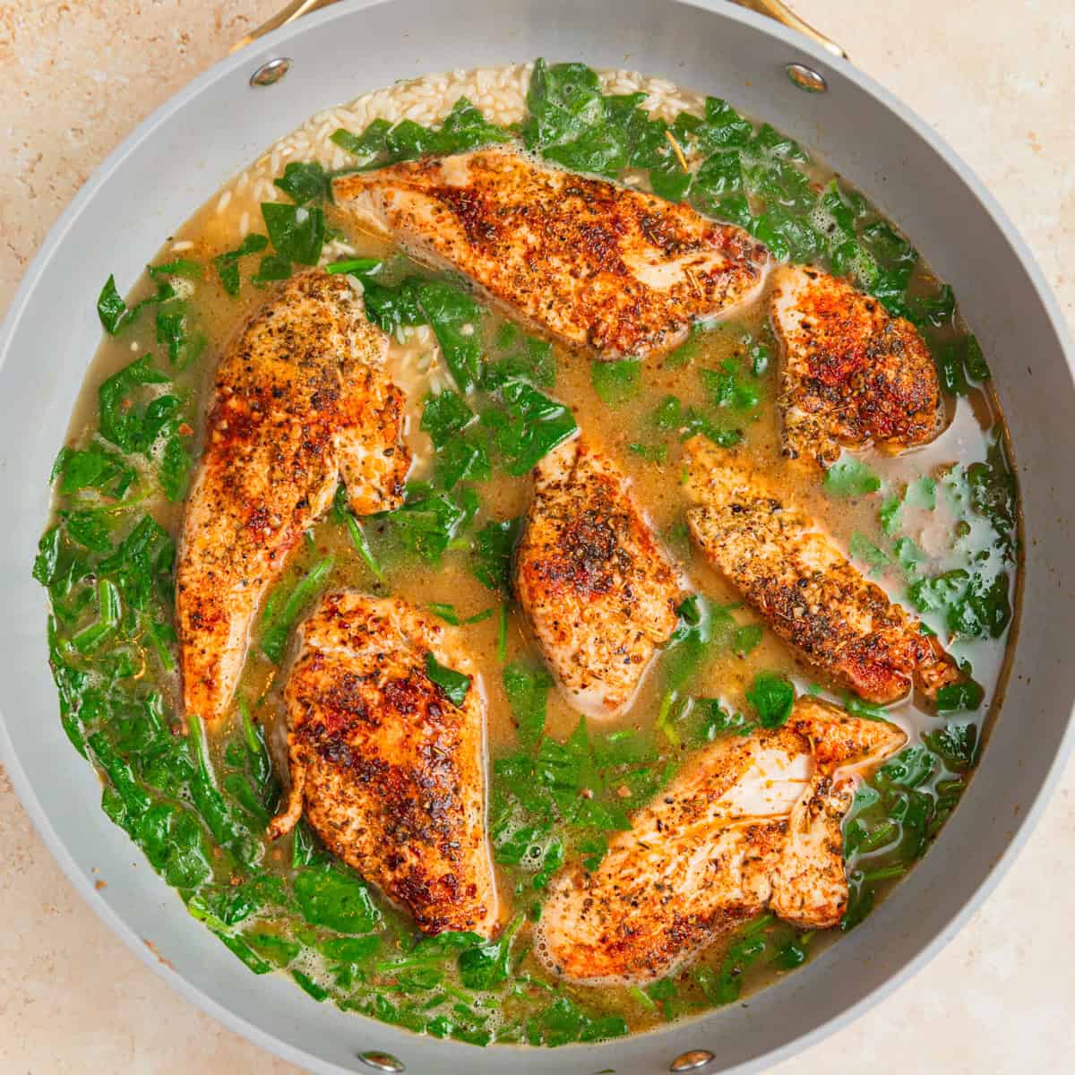 Chicken pieces added to pan with broth and rice.
