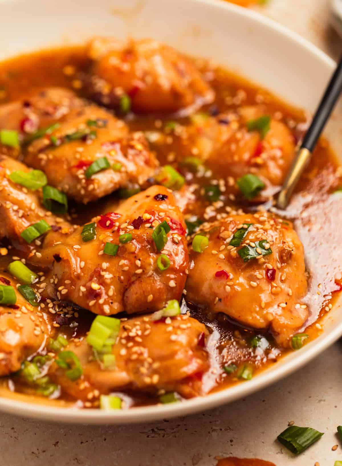 Bowl with slow cooker apricot chicken served with chopped green onions on top.