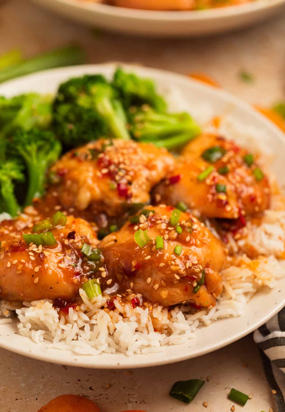 Plate with crockpot apricot chicken over rice and served with broccoli.