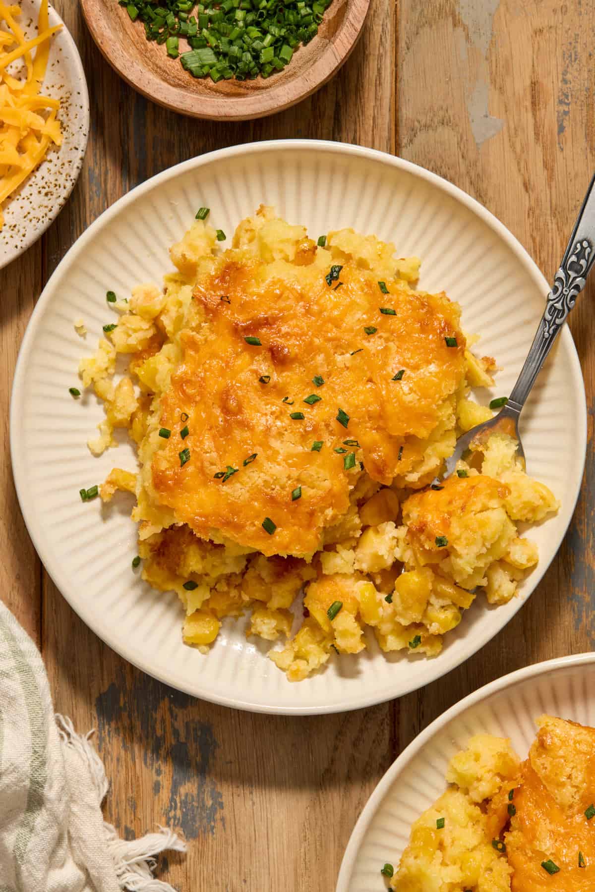Cheesy cornbread casserole served on plate with chopped chives.