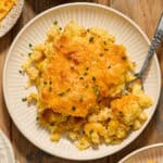 Cheesy cornbread casserole on white dish with fork scooping in.