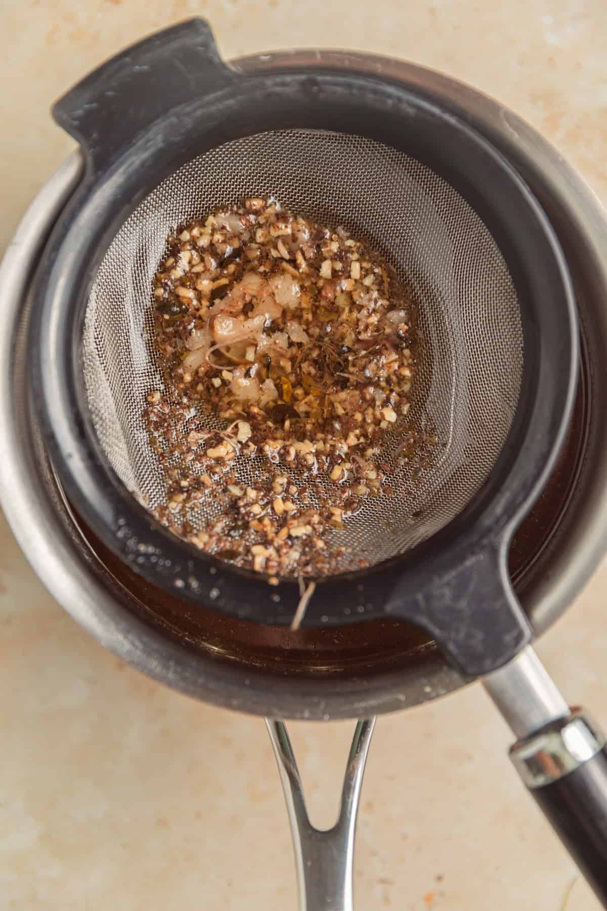 Strainer over saucepan catching drippings.