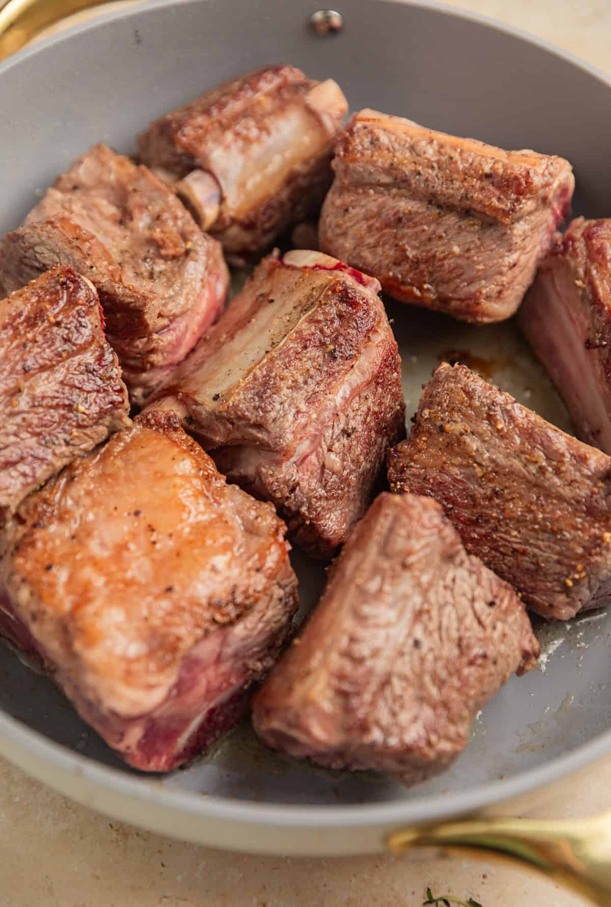 Seared short ribs in skillet.
