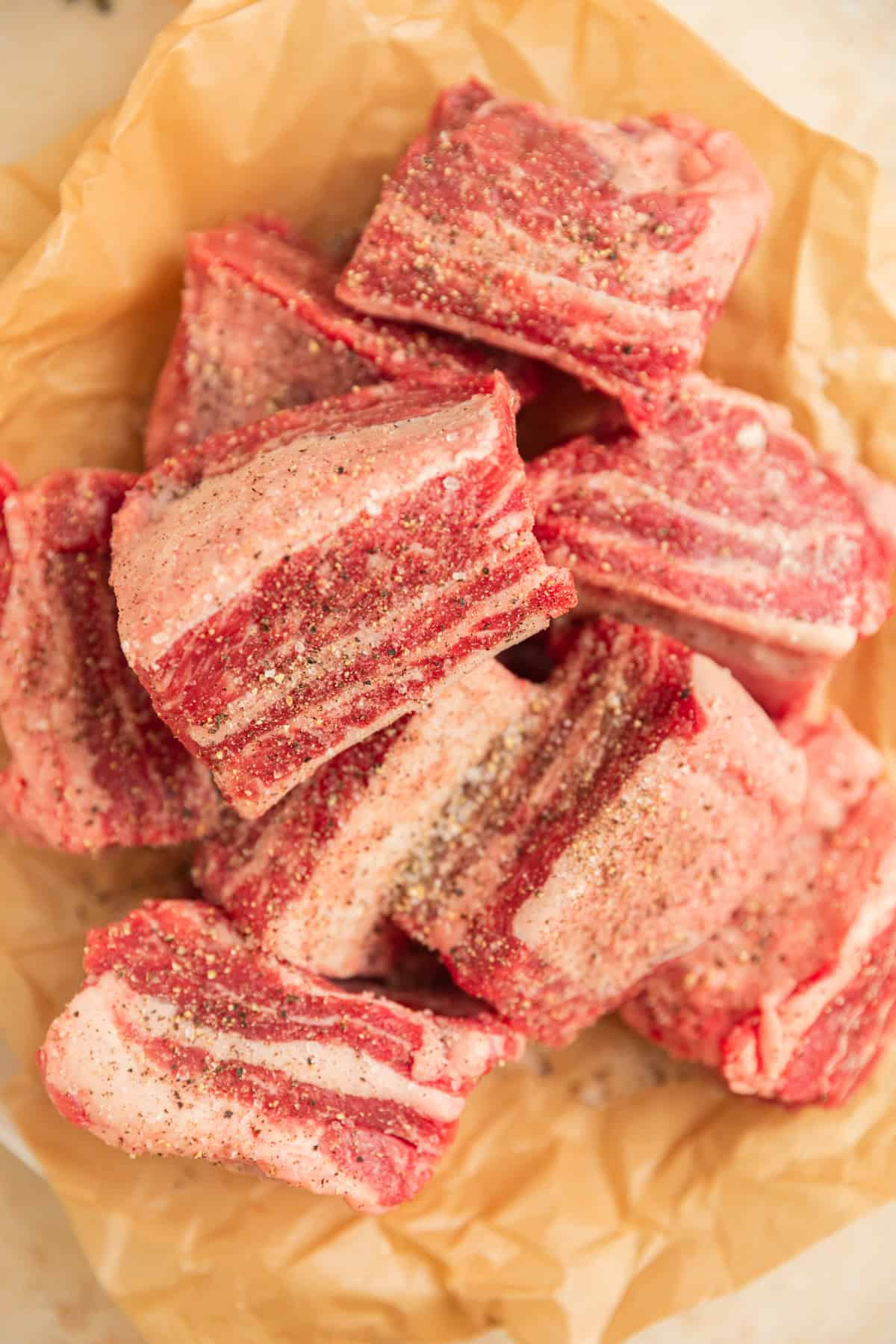 Seasoned short ribs in parchment before searing.