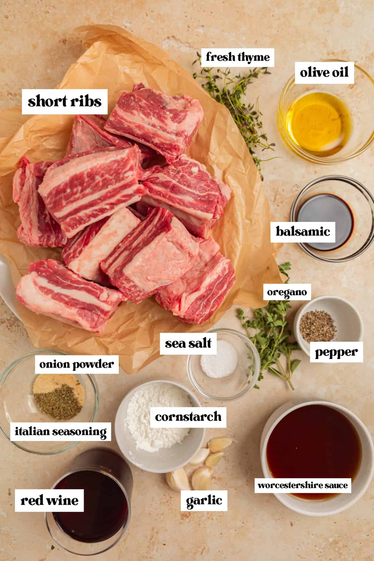 Short ribs in parchment, olive oil, red wine, and other ingredients arranged on surface.
