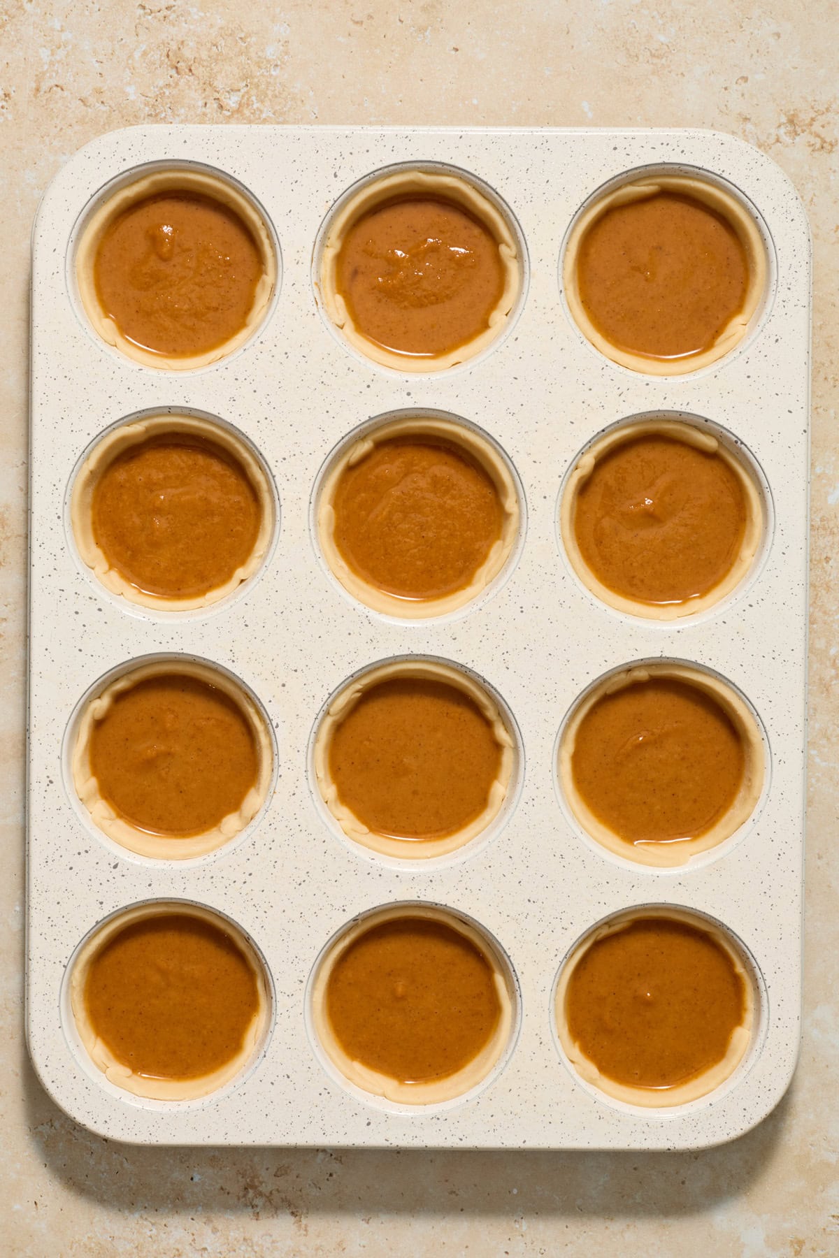 Muffin tin with mini pumpkin pies before baking.