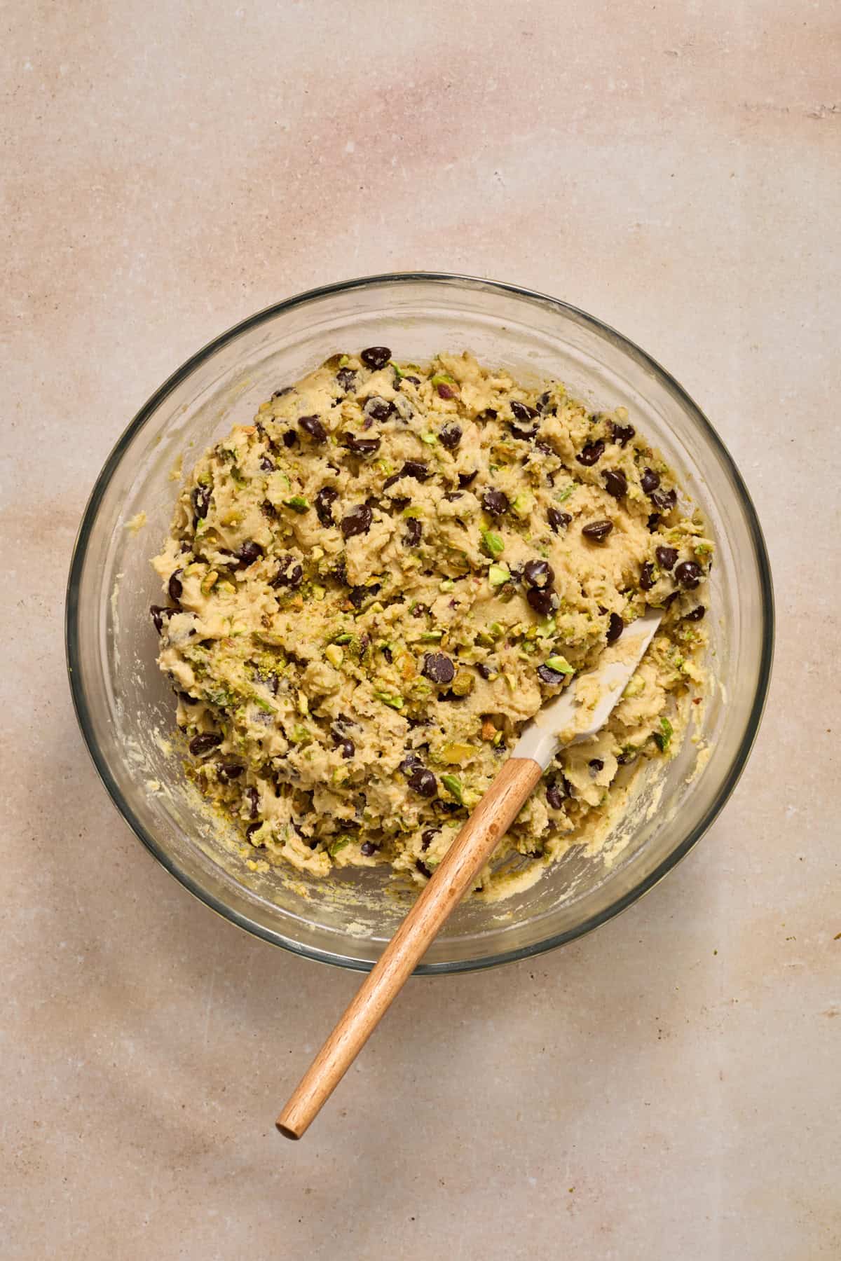 Pistachio chocolate chip cookie dough in bowl with spatula.