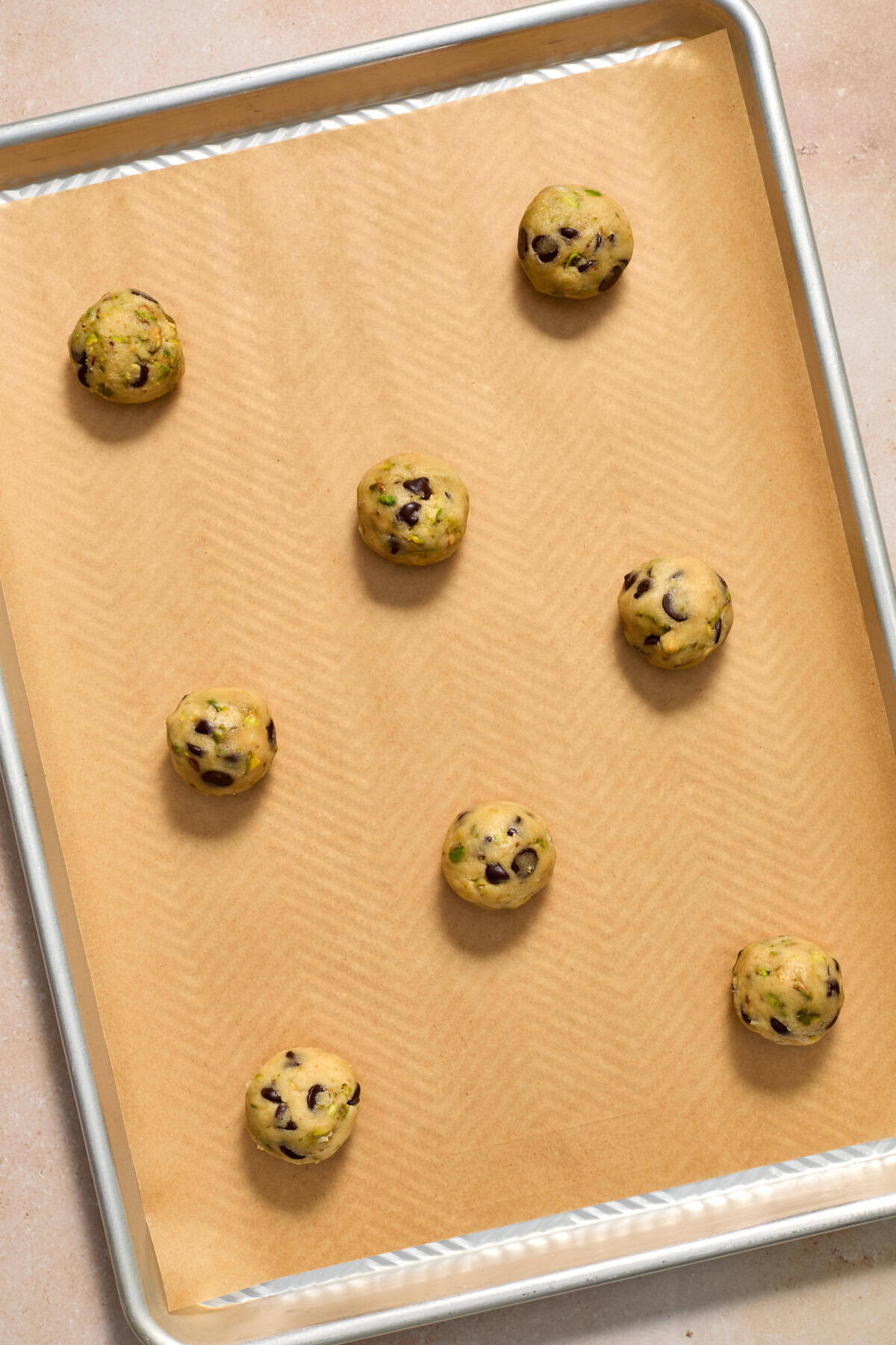Cookie dough balls on parchment lined baking sheet.