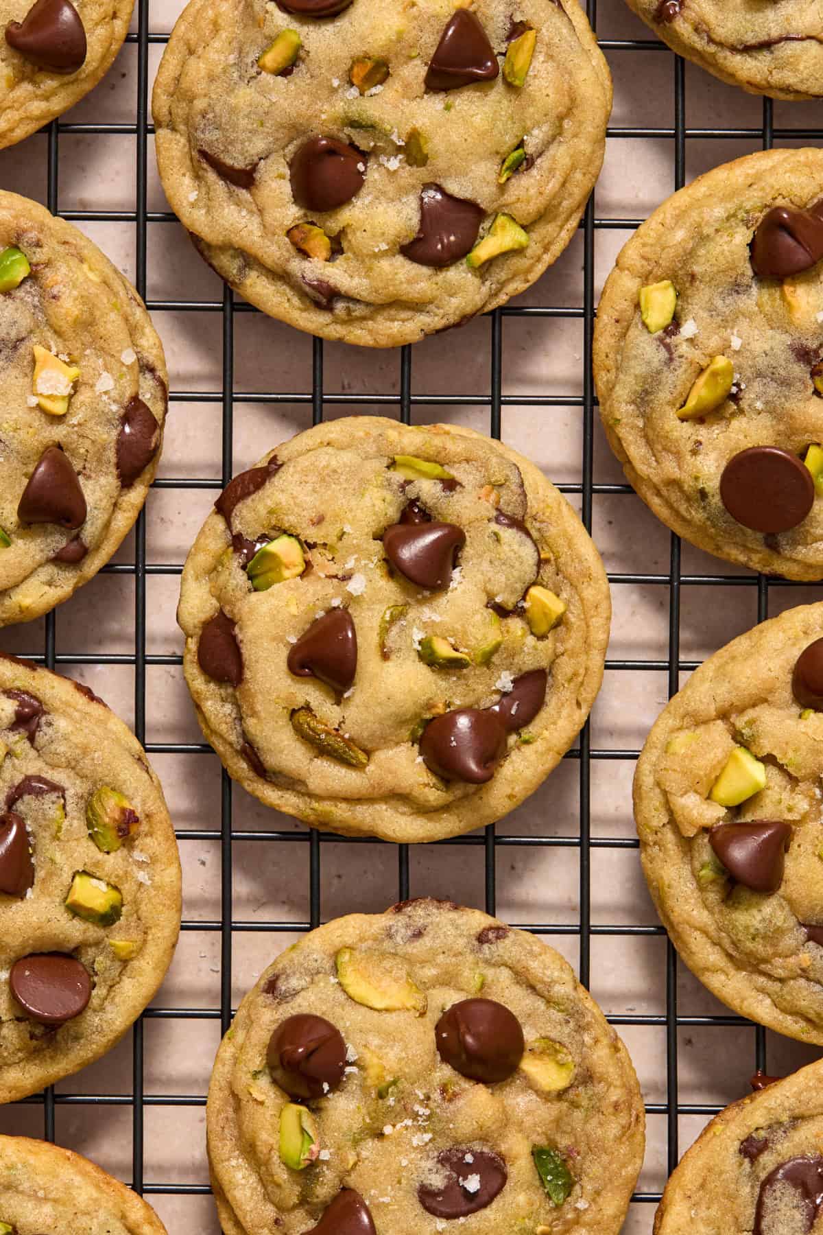 Wire rack with pistachio chocolate chip cookies cooling.