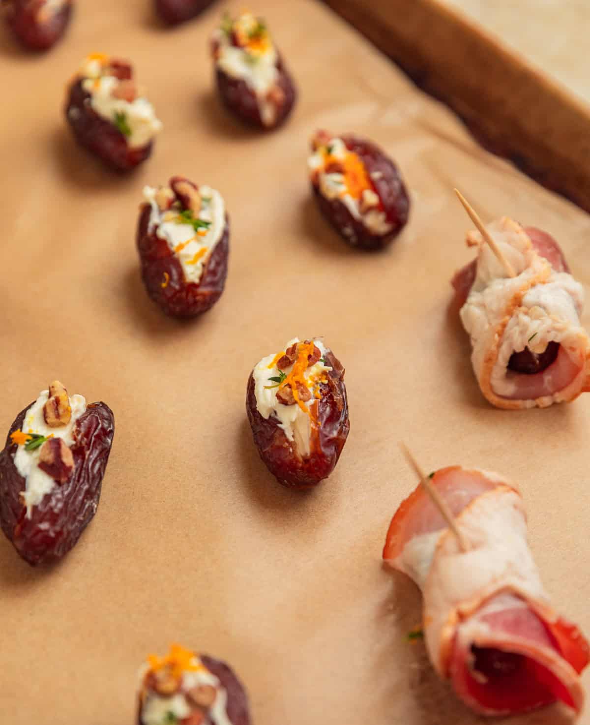 Dates stuffed with feta and topped with pecans and thyme on parchment.