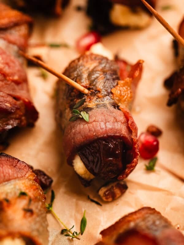 Bacon wrapped dates stuffed with honey whipped feta on parchment.