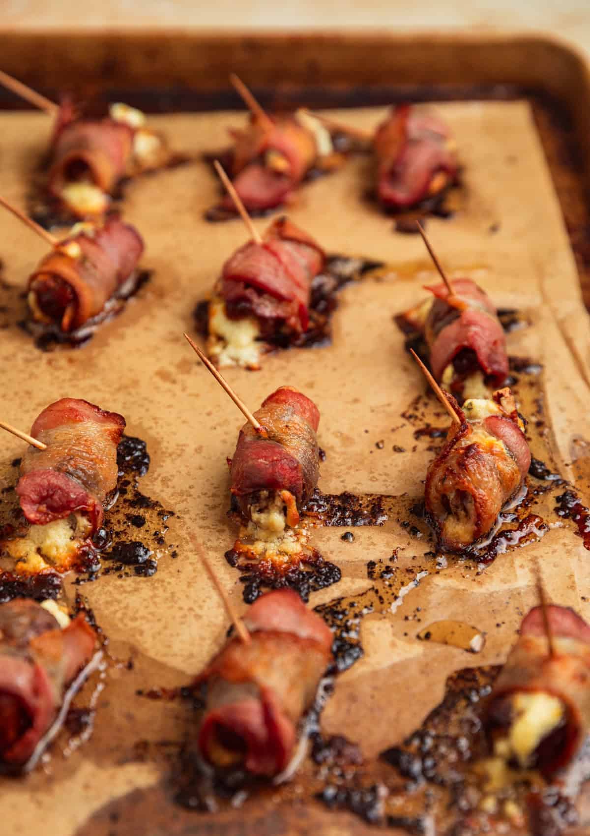Cooked bacon wrapped stuffed dates on pan.