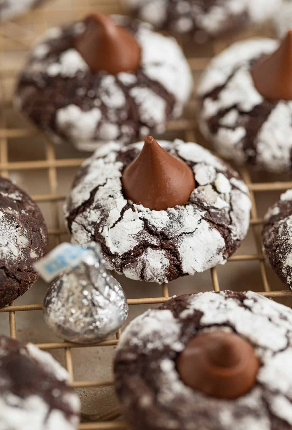 Chocolate crinkle cookies with hershey kiss centers on wire rack.