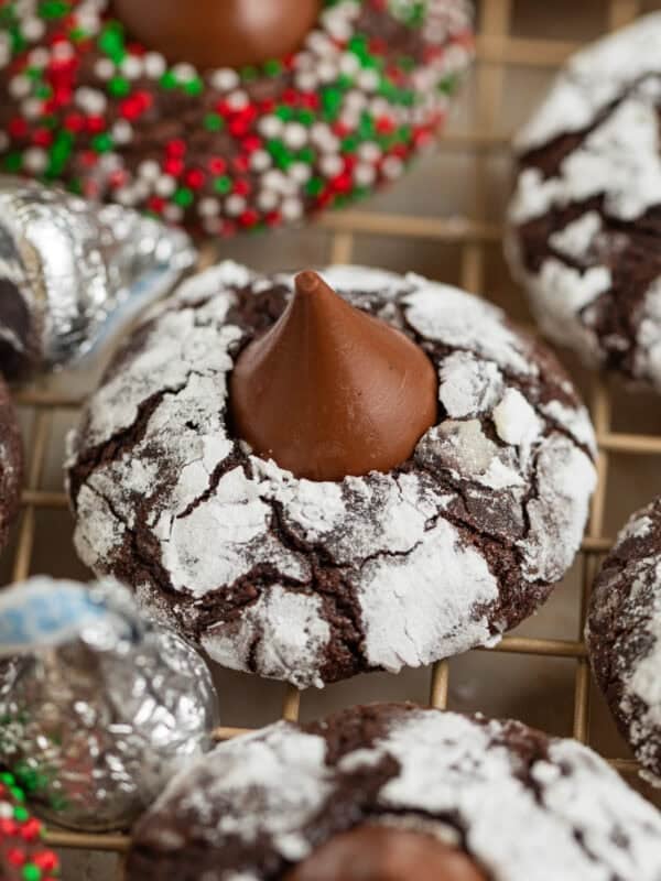 Chocolate crinkle cookies with hershey kiss centers on wire rack.