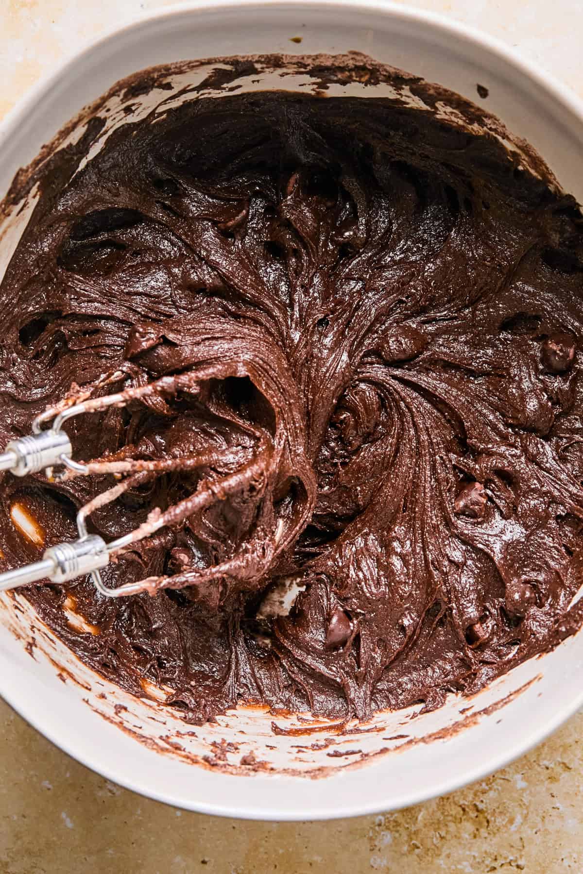 Beaten brownie cookie dough in bowl with mixer.