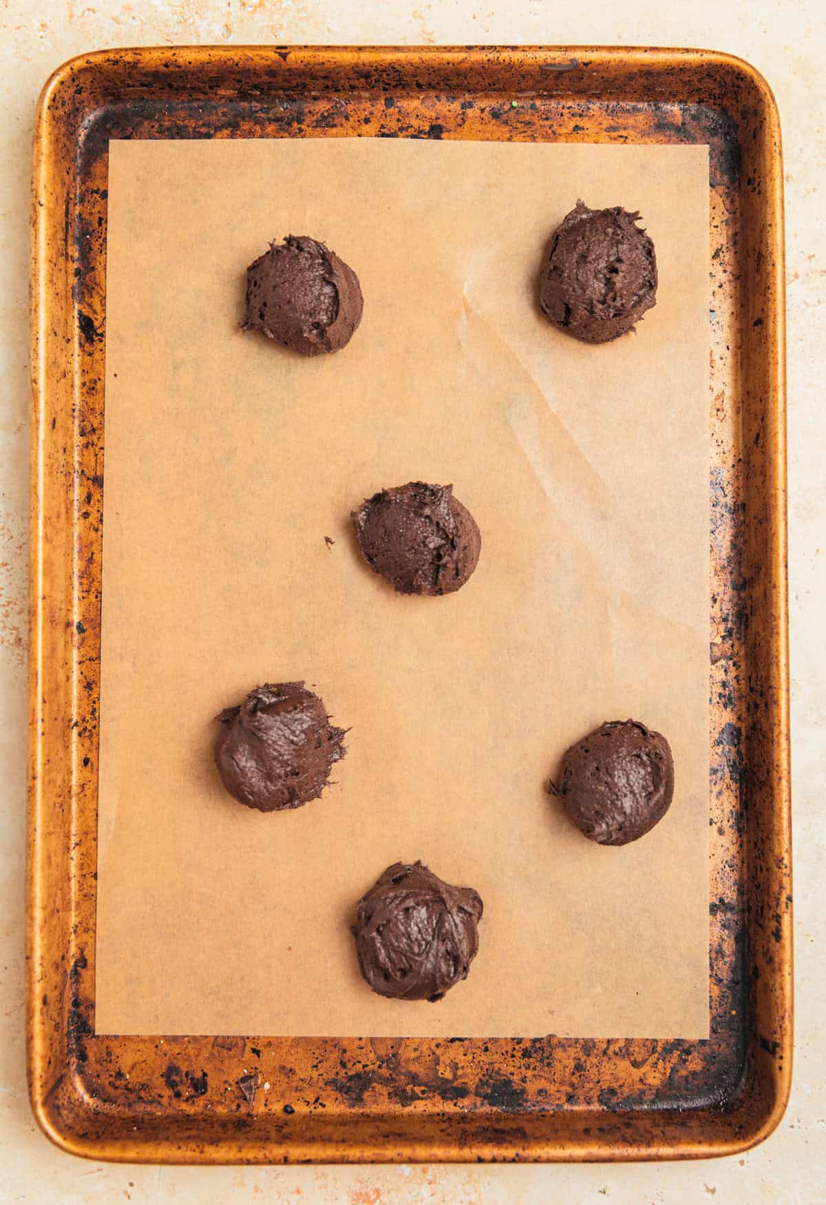 Chocolate cookie dough scooped onto parchment lined cookie sheet.