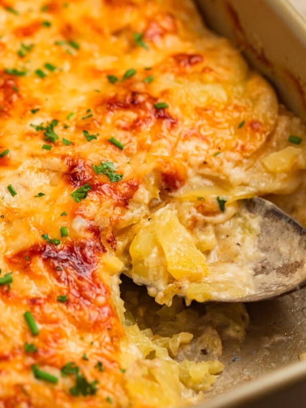 Gruyere scalloped potatoes in pan with serving spoon.