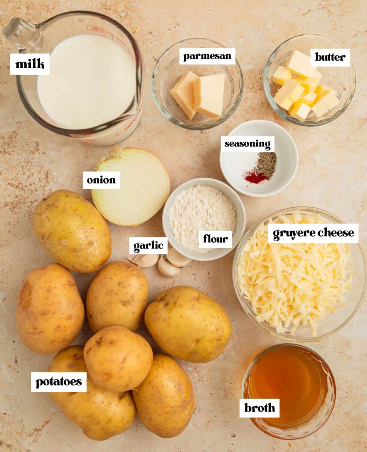 Labeled ingredients on surface including cheese, potatoes, and more.