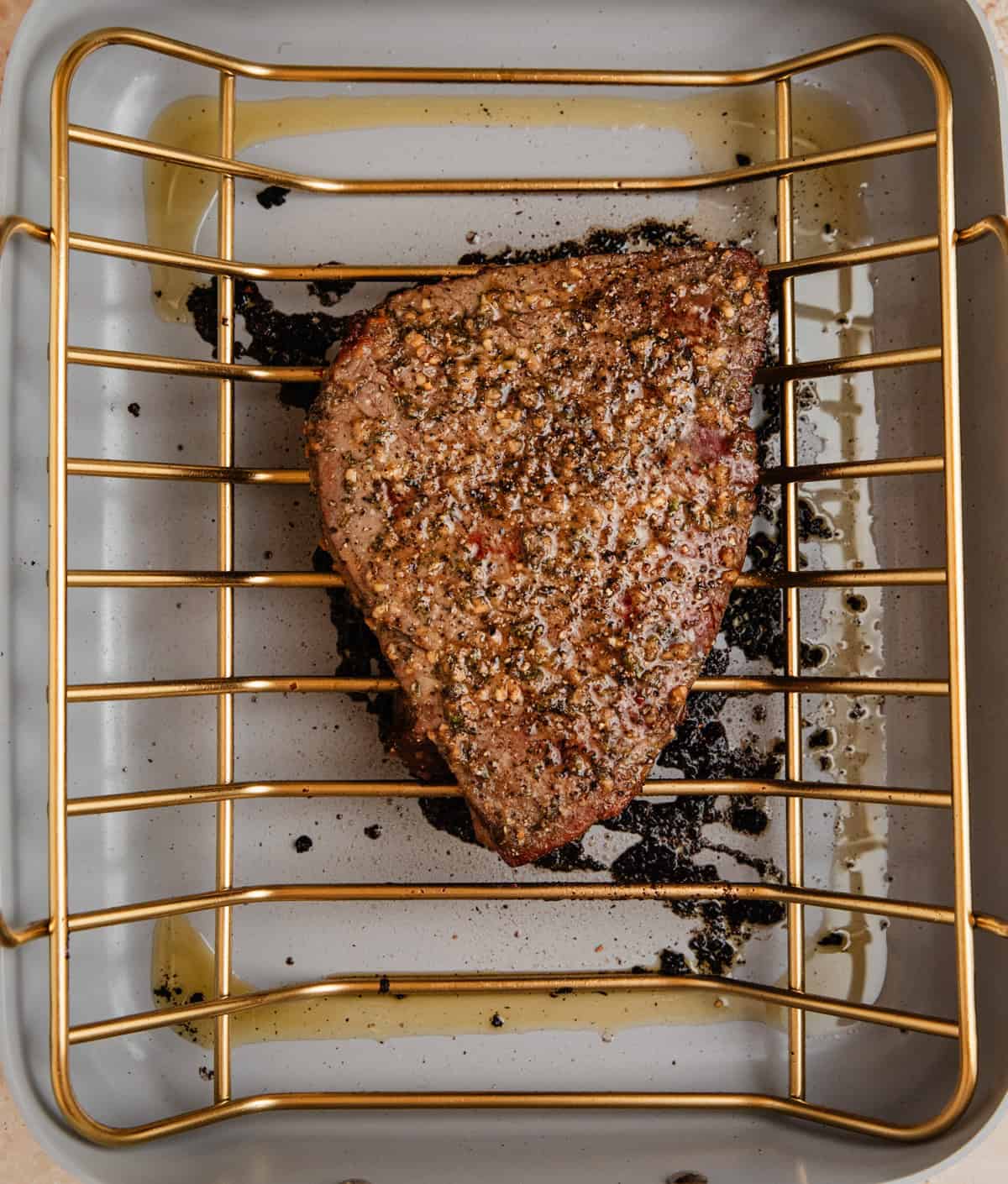 Cooked top round roast beef in roasting pan.