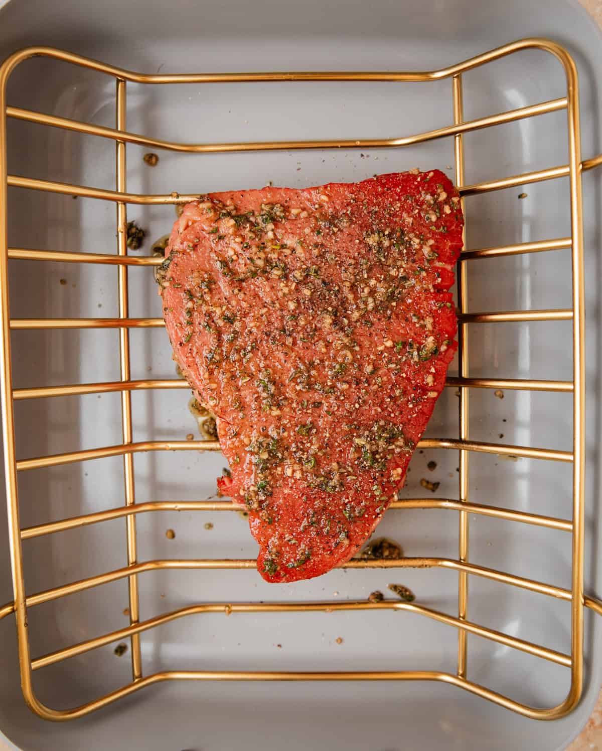 Roasting pan with top round roast with herb rub coating it before cooking.