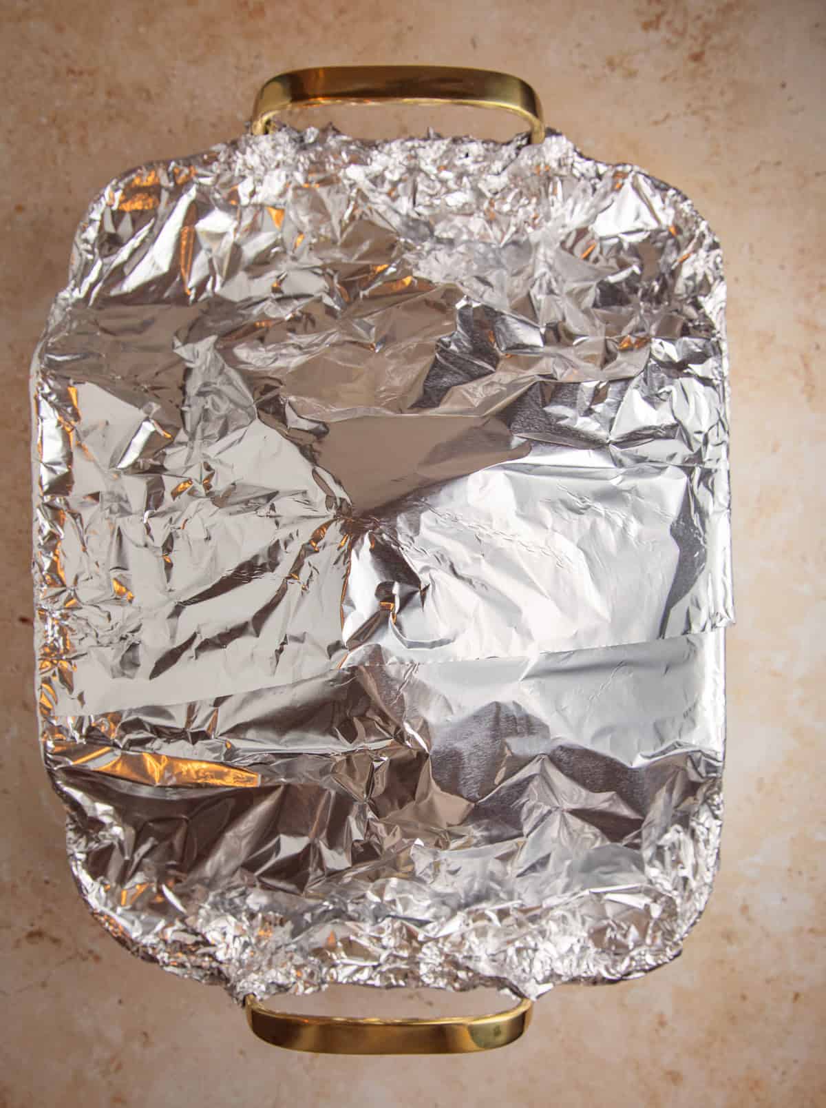 Foul covering ham in roasting pan.